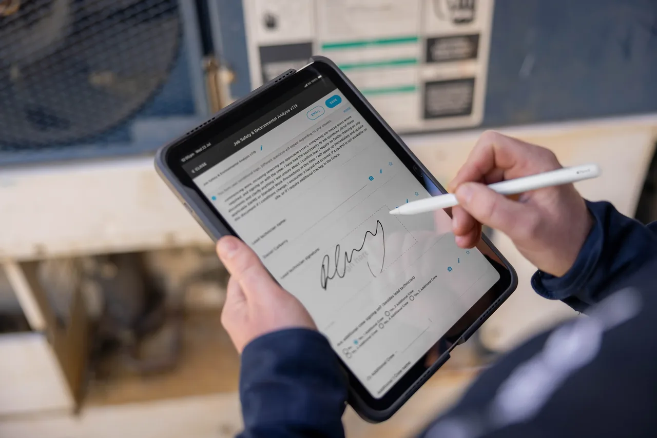 A Tonkin technician completing a form on an iPad in the field
