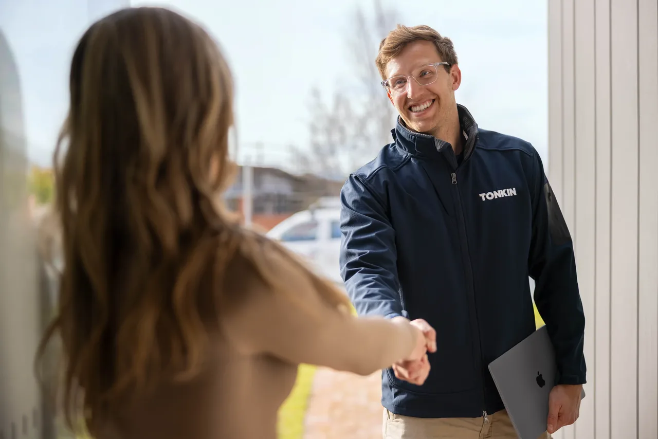 A Tonkin team member greeting a colleague with a MacBook